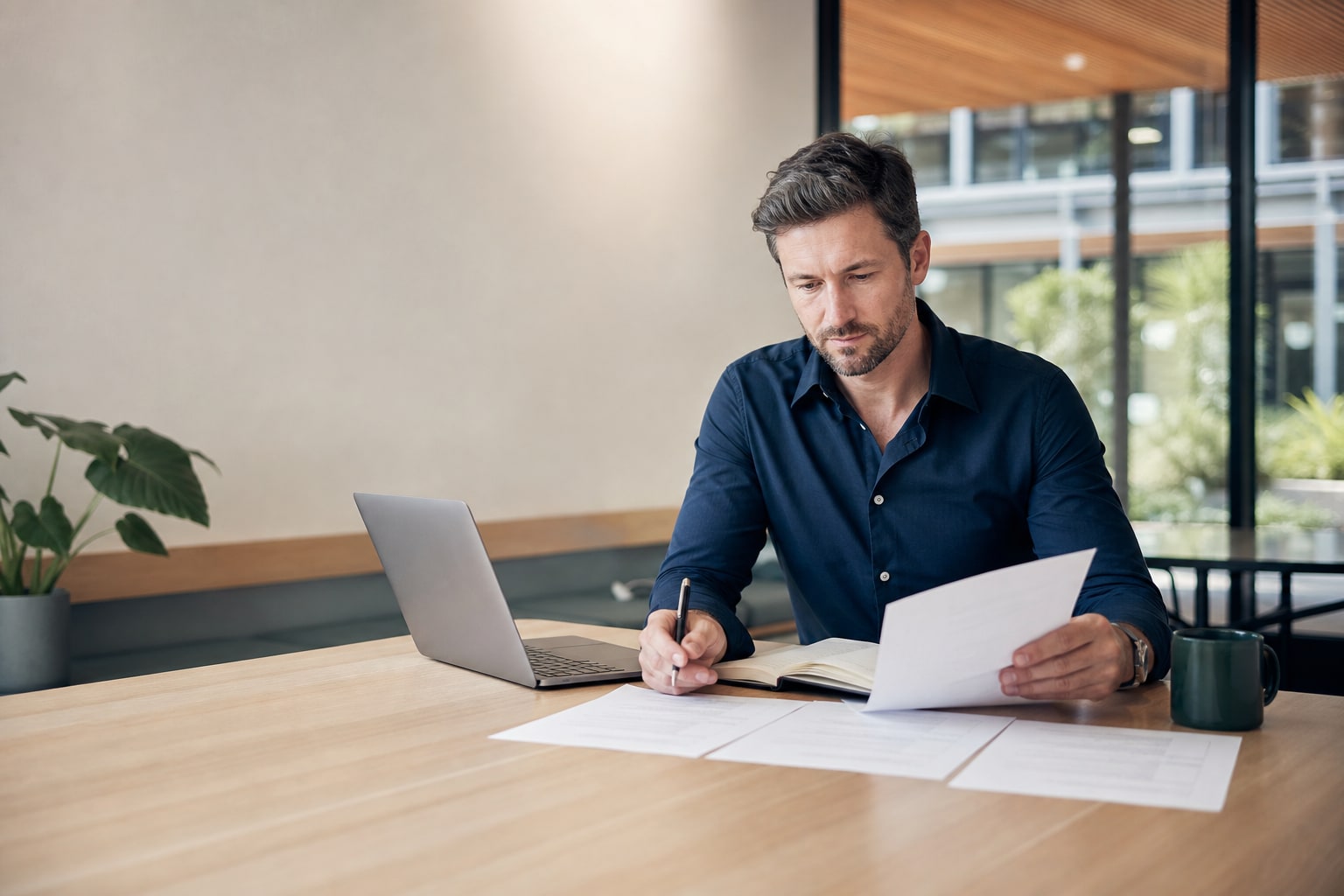 Experienced Australian professional comparing role information and making notes beside a laptop in a contemporary workplace.